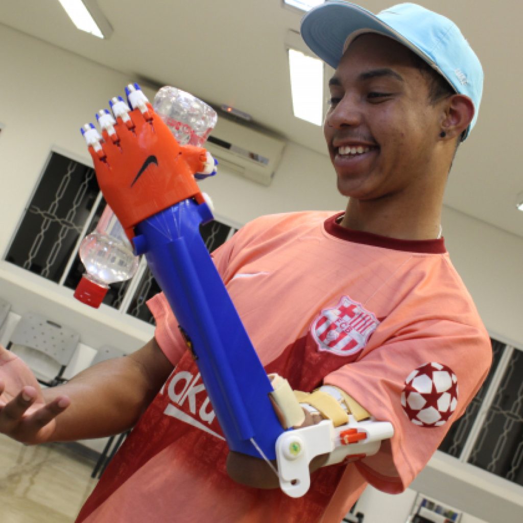 Rapaz com um braço robótico segura uma garrafa de água
